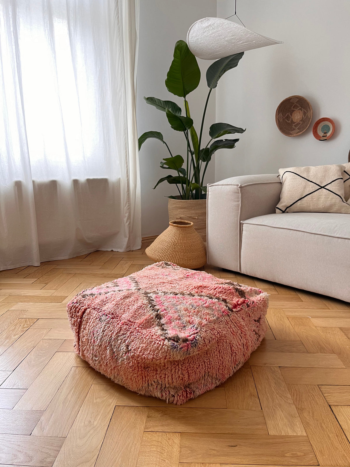 Bodenkissen aus vintage Beni-Ourain für Wohnzimmer oder Kinderzimmer. Sitzsack oder Stapelstein aus Kelim Teppichen in 60x60x25cm. Hergestellt in Handarbeit in Marrakesch. Beispielbild vor heller Couch.